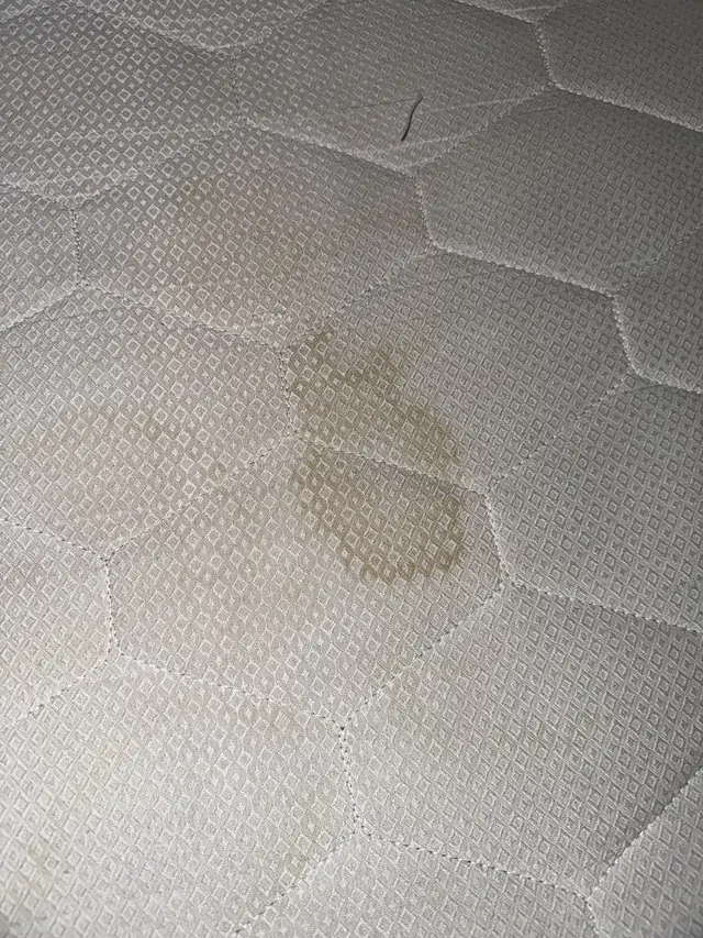 Husă de saltea cu model hexagonal înainte de curățare, cu o pată gălbuie
